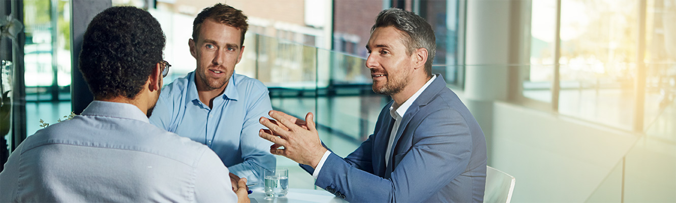 A group of business men collaborate while sitting.